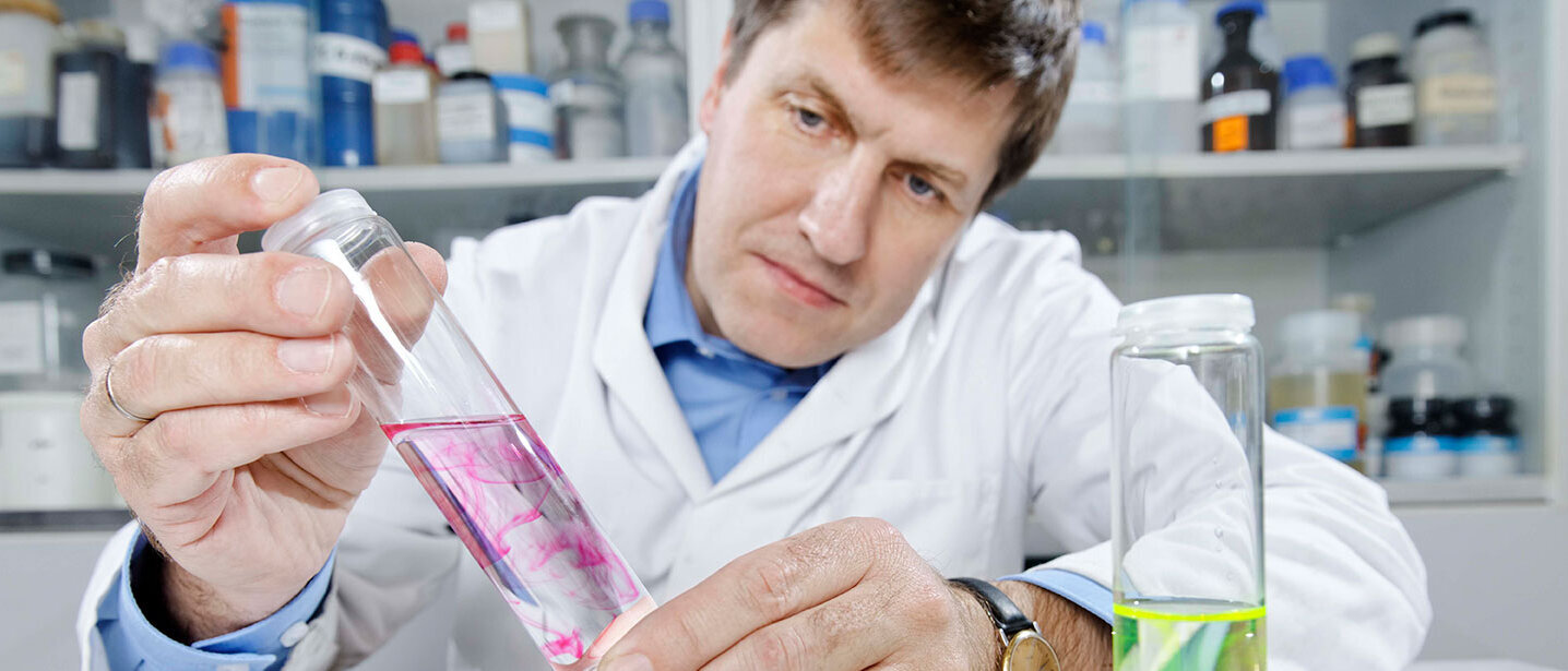Employee holds a test tube with a chemical liquid