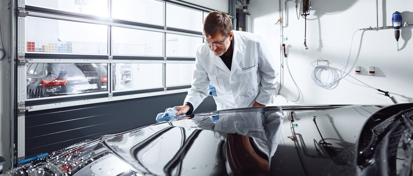 Engineer polishing and checking the hood of a black car