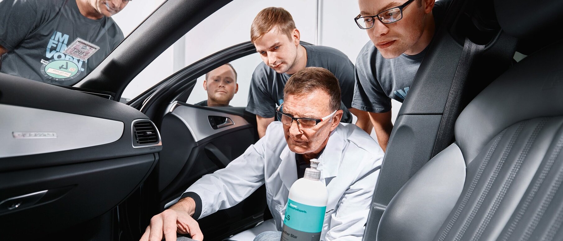Employee showing how to apply leather care on a car seat