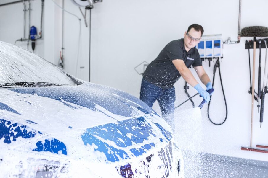 Photo of an employee shampooing a car with a pressure washer