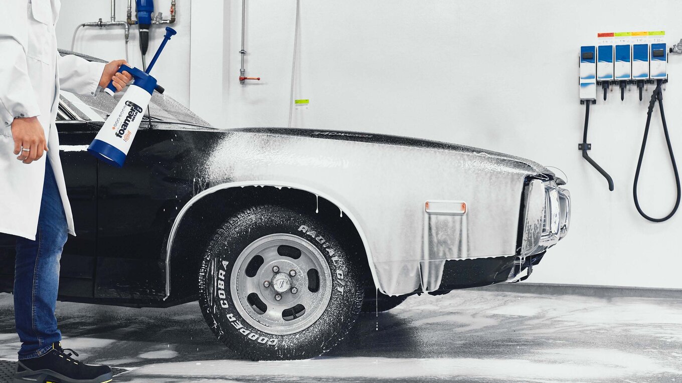 The front of a black muscle car covered in white foam