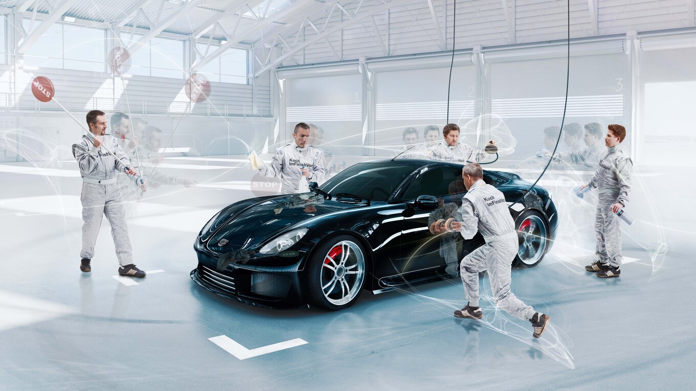 Employees cleaning a black sports car in a pit stop situation