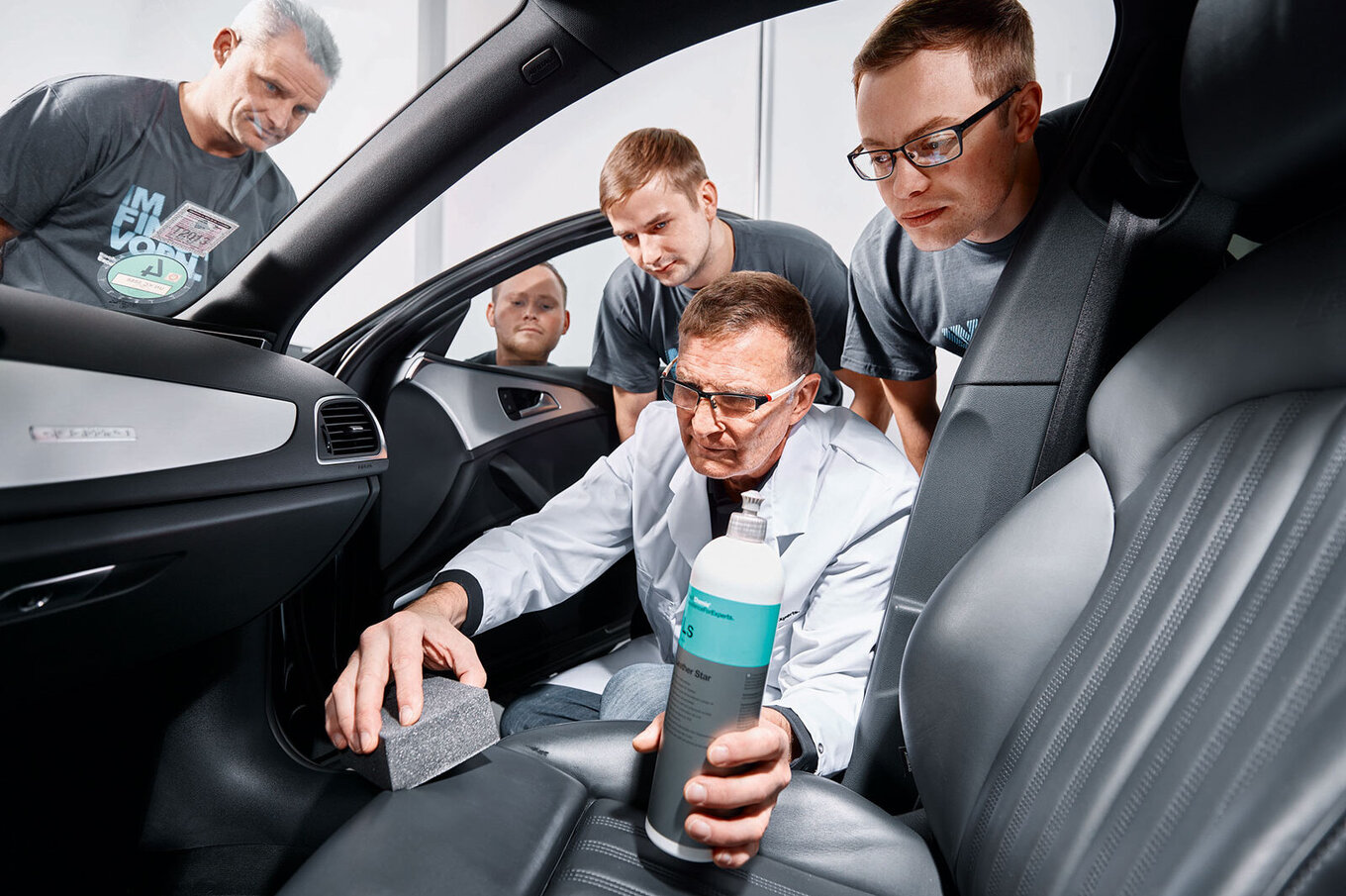 Employee showing how to apply leather care on a car seat