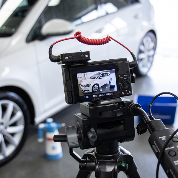 Making-of shot of a camera filming the cleaning process of a car