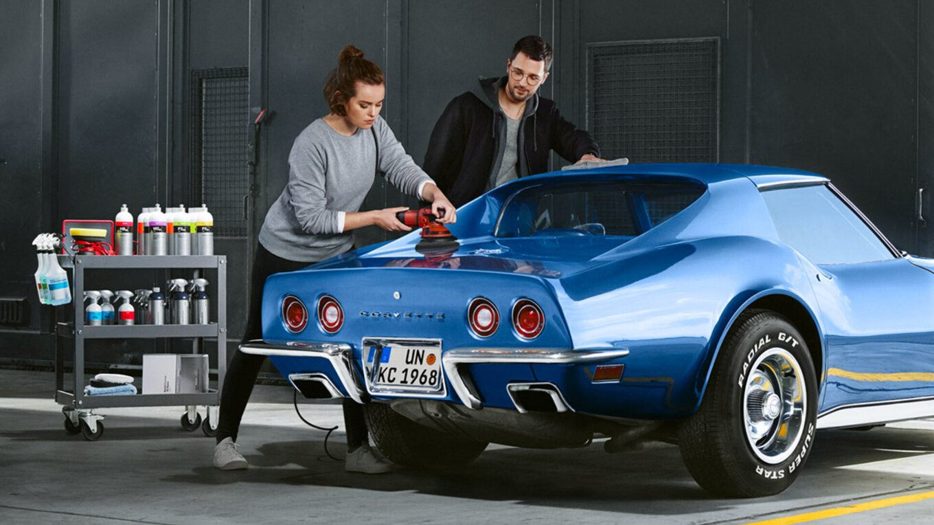 Woman and man polishing a blue Corvette